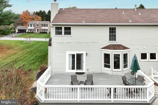 back of property with a deck and a lawn