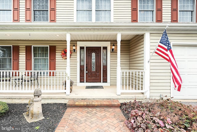 view of exterior entry featuring covered porch and a garage