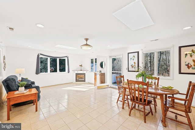 dining area featuring light tile patterned floors and a skylight