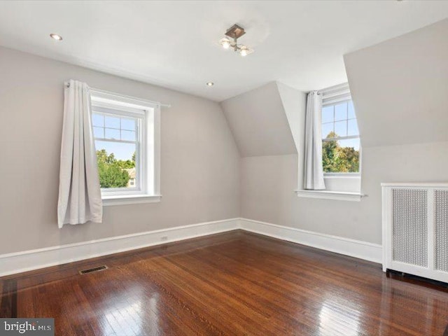 bonus room featuring a healthy amount of sunlight, radiator heating unit, and dark wood-type flooring