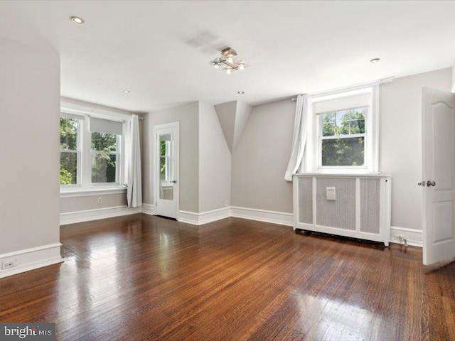 empty room with dark hardwood / wood-style floors and radiator