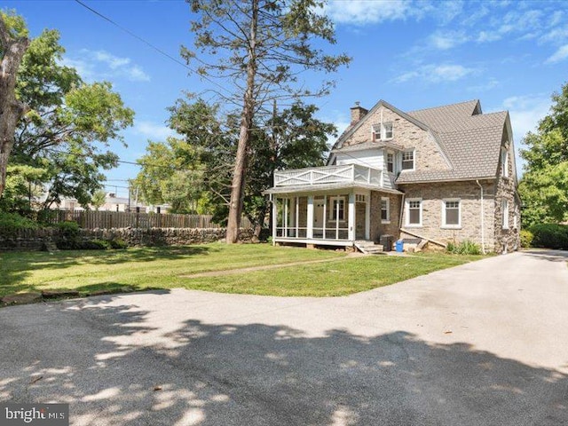 view of front facade with a front yard and a sunroom