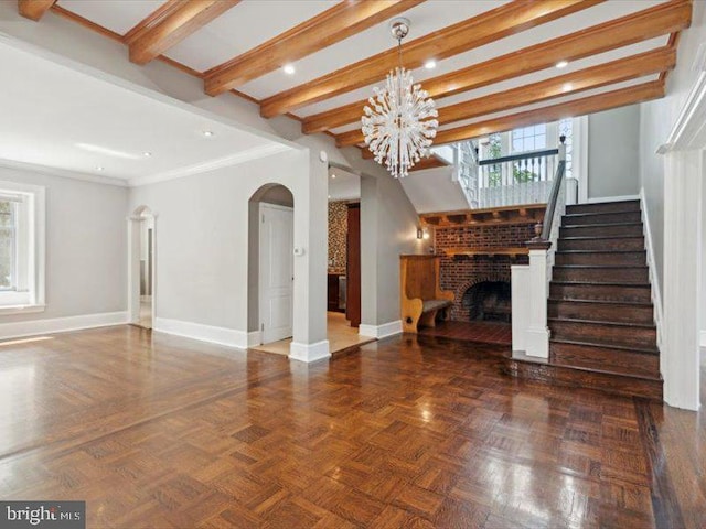 unfurnished living room featuring dark parquet flooring, ornamental molding, an inviting chandelier, beamed ceiling, and a fireplace