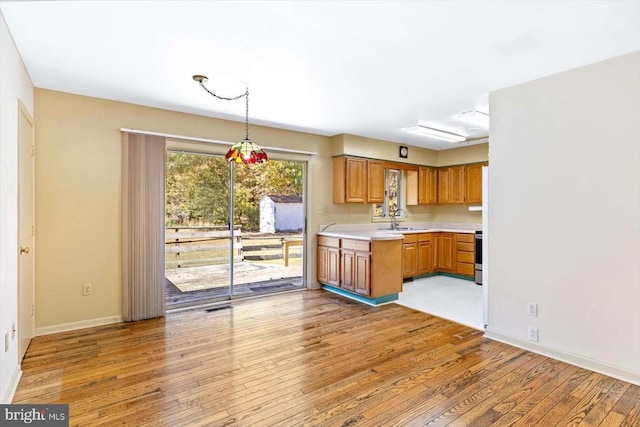 kitchen with sink, pendant lighting, stainless steel electric range, and light wood-type flooring