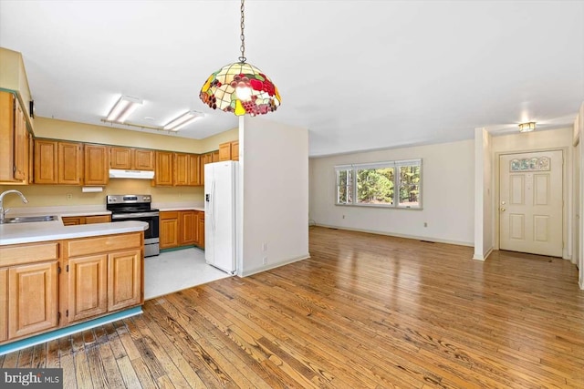 kitchen featuring sink, white refrigerator with ice dispenser, pendant lighting, stainless steel electric range, and light wood-type flooring