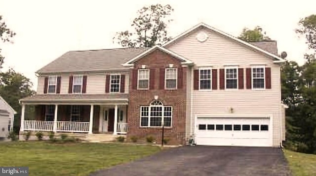 view of front of property featuring a garage, covered porch, and a front lawn