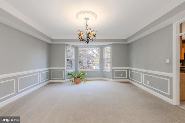 spare room featuring a notable chandelier, light carpet, and crown molding