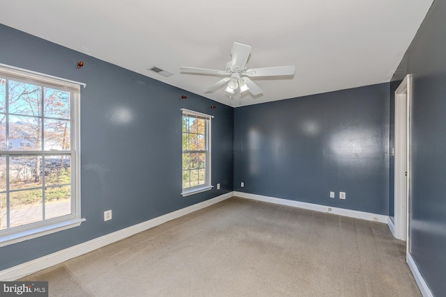 carpeted empty room with a wealth of natural light and ceiling fan