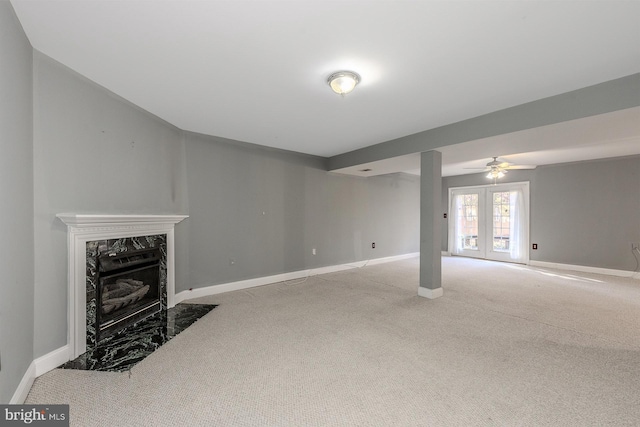 unfurnished living room featuring a fireplace, ceiling fan, light carpet, and french doors