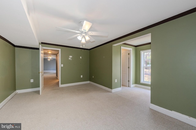 carpeted spare room featuring ceiling fan and crown molding