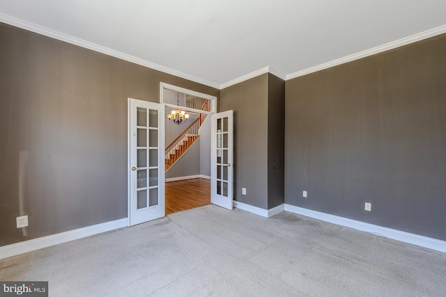 carpeted spare room featuring an inviting chandelier, french doors, and ornamental molding