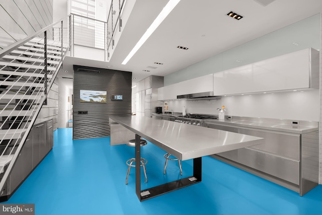 kitchen featuring white cabinets, ventilation hood, stainless steel stove, and stainless steel counters