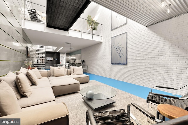 living room with a towering ceiling and brick wall