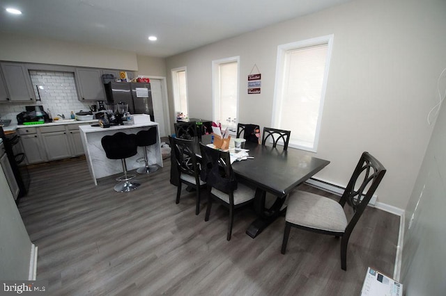 dining space featuring dark wood-type flooring and a baseboard heating unit