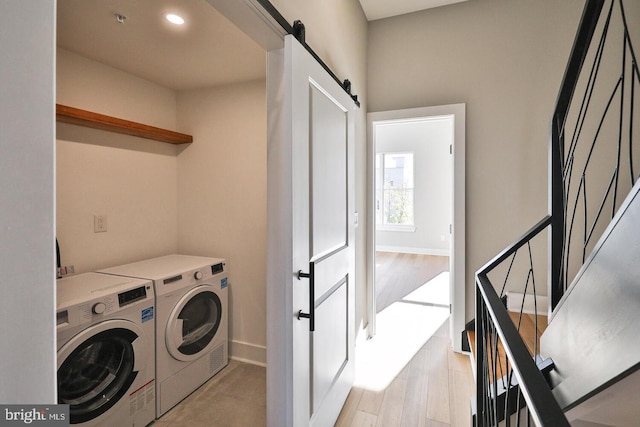 laundry area with light wood-type flooring, a barn door, and independent washer and dryer