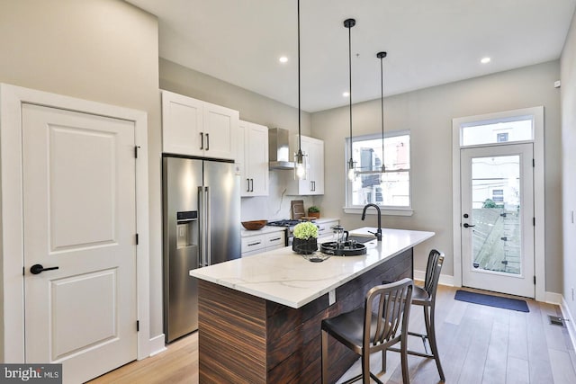 kitchen featuring white cabinetry, appliances with stainless steel finishes, light hardwood / wood-style floors, and a center island