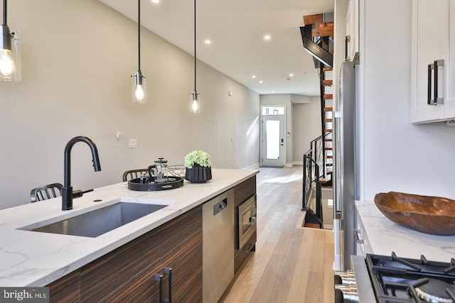 kitchen with decorative light fixtures, appliances with stainless steel finishes, sink, and light hardwood / wood-style floors