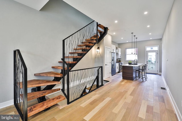 stairway featuring a chandelier, hardwood / wood-style flooring, and sink