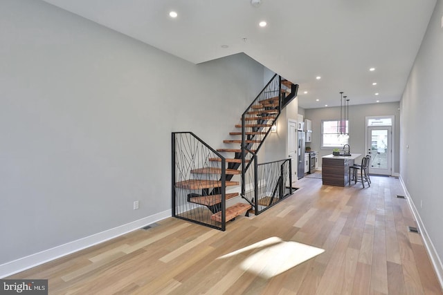 stairway featuring wood-type flooring and sink