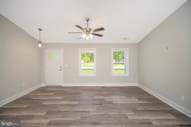 empty room with dark hardwood / wood-style flooring, ceiling fan, and vaulted ceiling