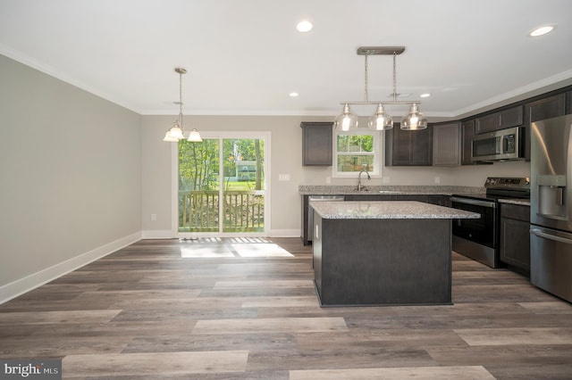 kitchen featuring dark brown cabinetry, appliances with stainless steel finishes, a kitchen island, dark wood-type flooring, and pendant lighting