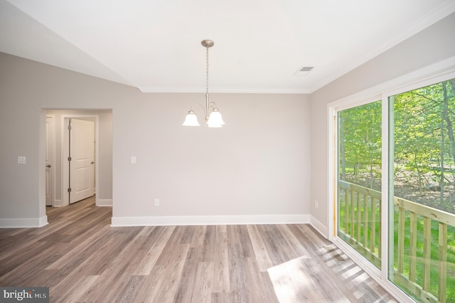 spare room featuring ornamental molding, hardwood / wood-style floors, a chandelier, and vaulted ceiling