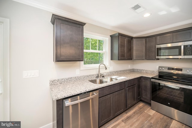 kitchen featuring stainless steel appliances, sink, ornamental molding, dark brown cabinets, and light hardwood / wood-style flooring