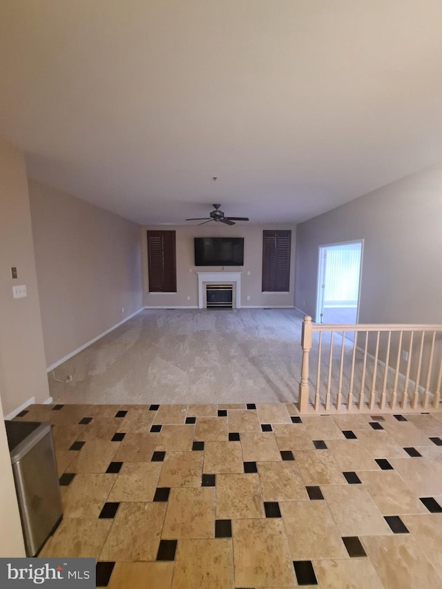 unfurnished living room featuring ceiling fan and light colored carpet