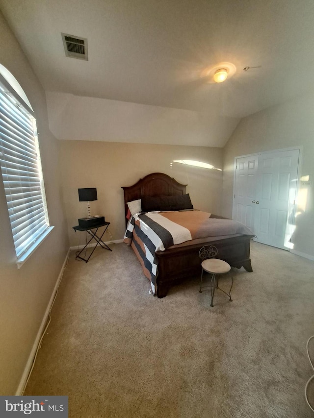 bedroom featuring a closet, light colored carpet, and vaulted ceiling