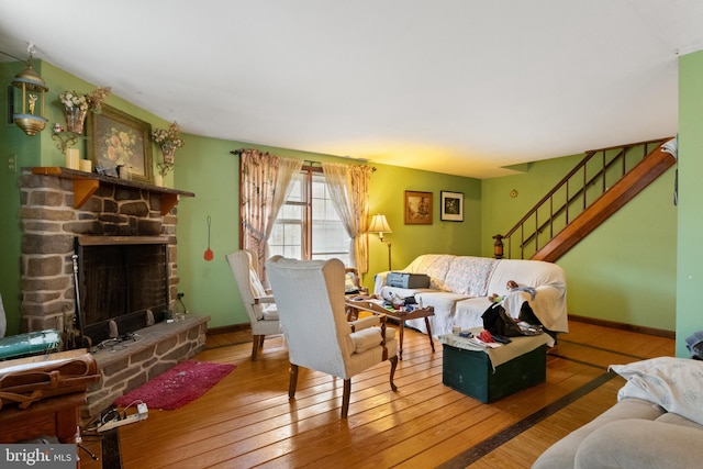 living room with hardwood / wood-style flooring and a stone fireplace