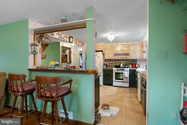 kitchen featuring a breakfast bar, white appliances, light tile patterned floors, light brown cabinetry, and kitchen peninsula