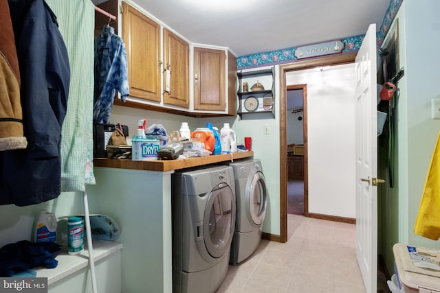 laundry room featuring washing machine and clothes dryer, light tile patterned floors, and cabinets