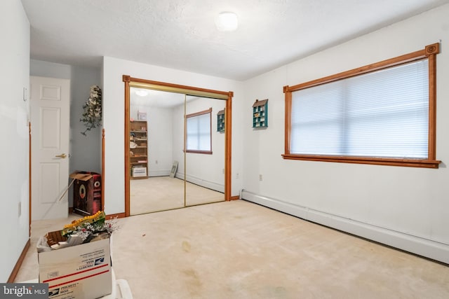 unfurnished bedroom featuring light carpet, a textured ceiling, a closet, and baseboard heating