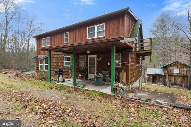 rear view of property with a patio and a storage shed