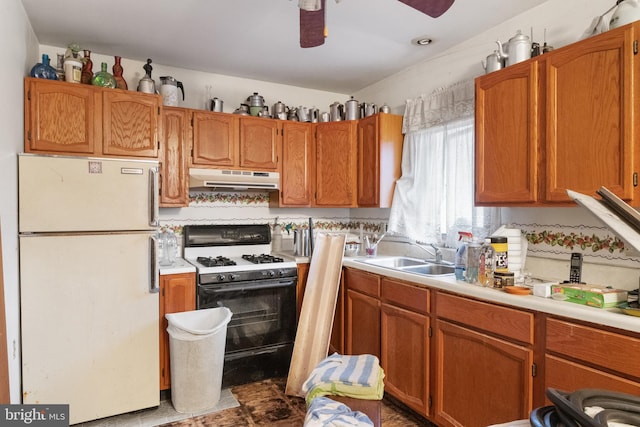 kitchen with black gas range, white fridge, ceiling fan, and sink