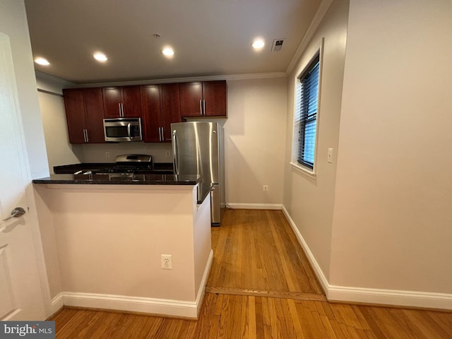 kitchen with kitchen peninsula, light hardwood / wood-style floors, appliances with stainless steel finishes, and ornamental molding