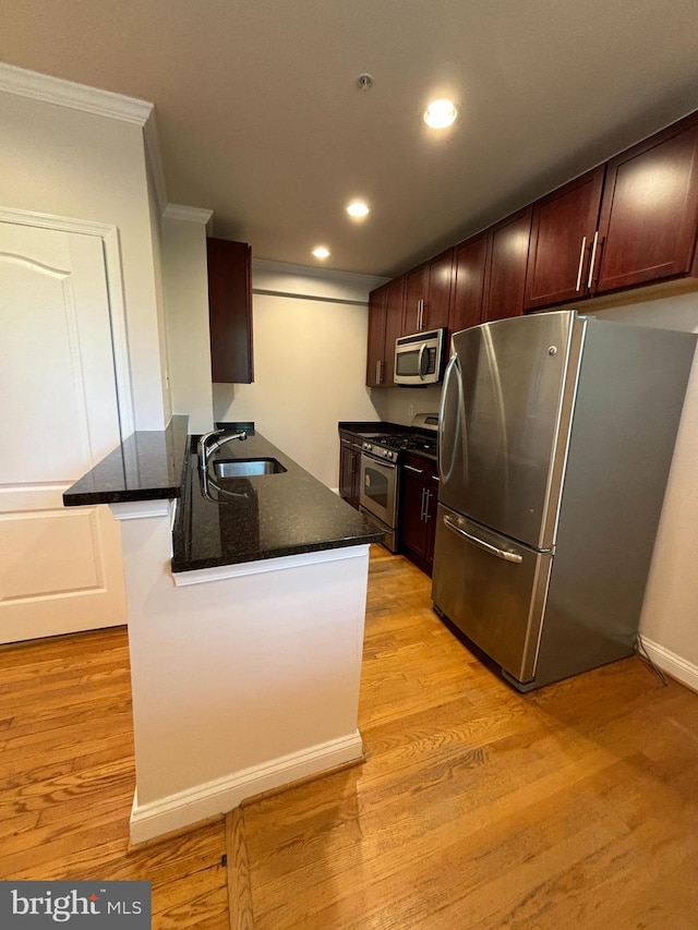 kitchen featuring appliances with stainless steel finishes, sink, crown molding, and light hardwood / wood-style flooring