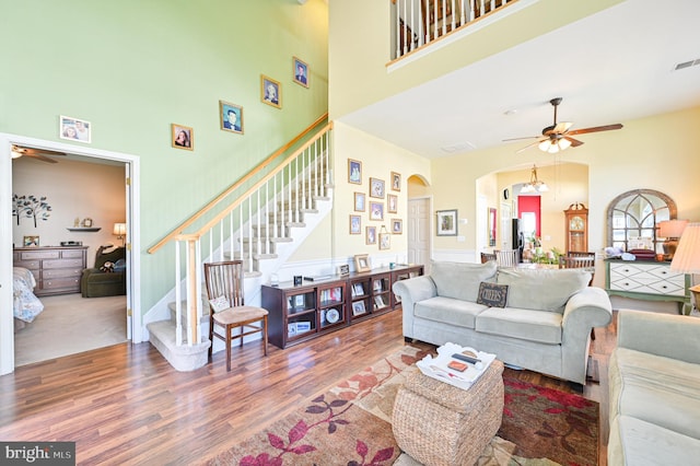 living room featuring hardwood / wood-style floors, a high ceiling, and ceiling fan