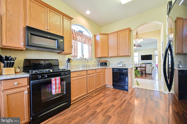 kitchen with light stone counters, black appliances, hardwood / wood-style flooring, sink, and ceiling fan