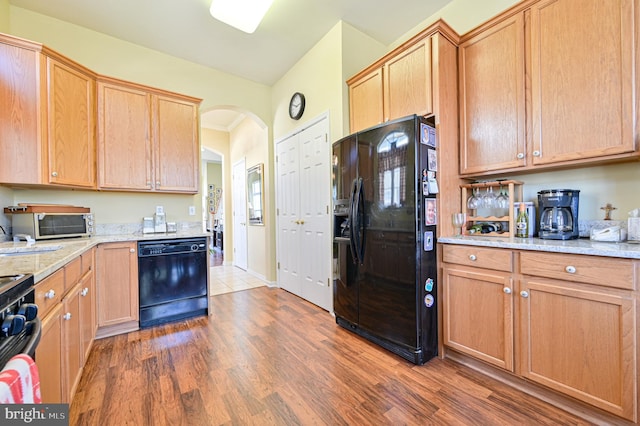 kitchen with ornamental molding, dark hardwood / wood-style flooring, black appliances, and light stone counters