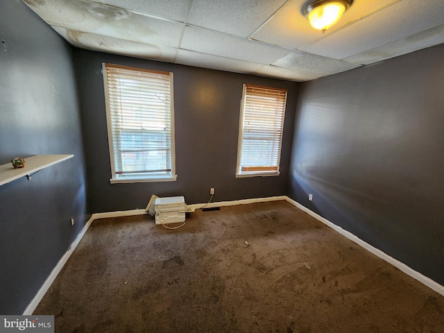 carpeted spare room featuring a drop ceiling and a healthy amount of sunlight