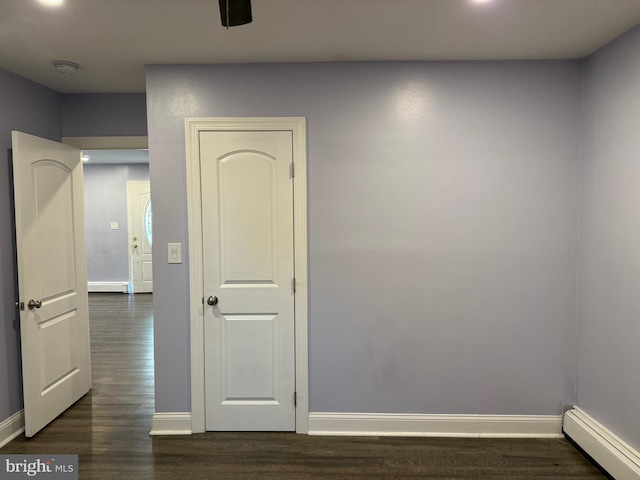 empty room featuring dark hardwood / wood-style flooring and a baseboard heating unit