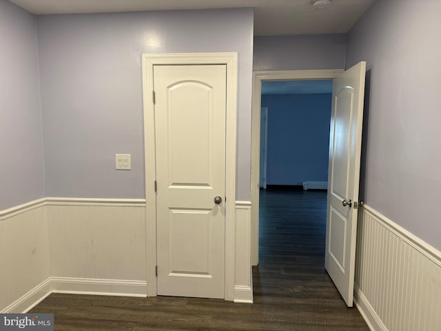 corridor with baseboard heating and dark wood-type flooring