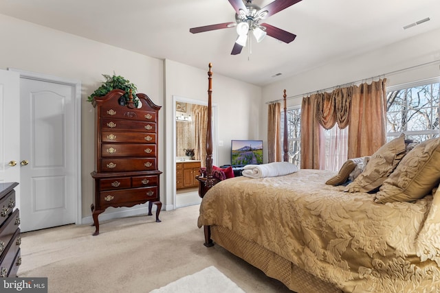 bedroom with light colored carpet, ceiling fan, and ensuite bathroom