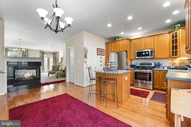 kitchen with an inviting chandelier, decorative light fixtures, stainless steel appliances, and a kitchen island