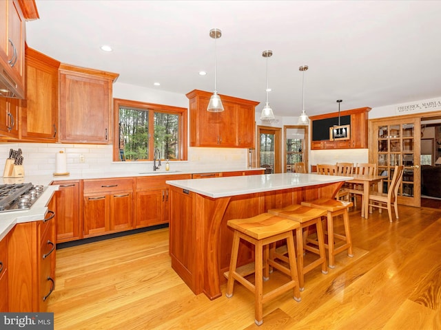 kitchen with a center island, sink, a kitchen breakfast bar, pendant lighting, and light wood-type flooring