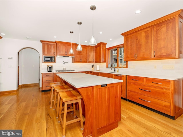 kitchen featuring stainless steel gas stovetop, sink, light hardwood / wood-style floors, a kitchen island, and black microwave