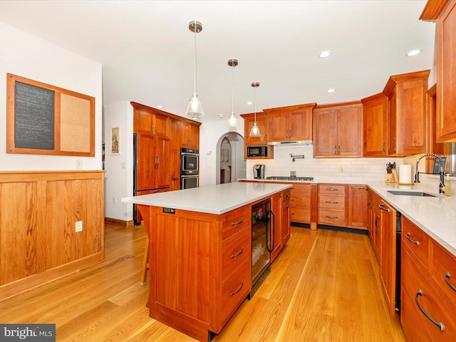 kitchen with decorative light fixtures, a center island, light hardwood / wood-style floors, and sink