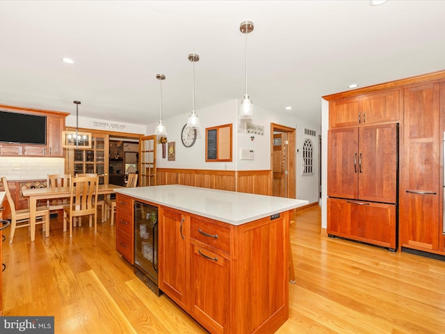 kitchen featuring decorative light fixtures, paneled built in fridge, a kitchen island, and wine cooler