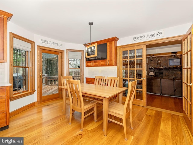 dining area with a wealth of natural light, light hardwood / wood-style flooring, and an inviting chandelier